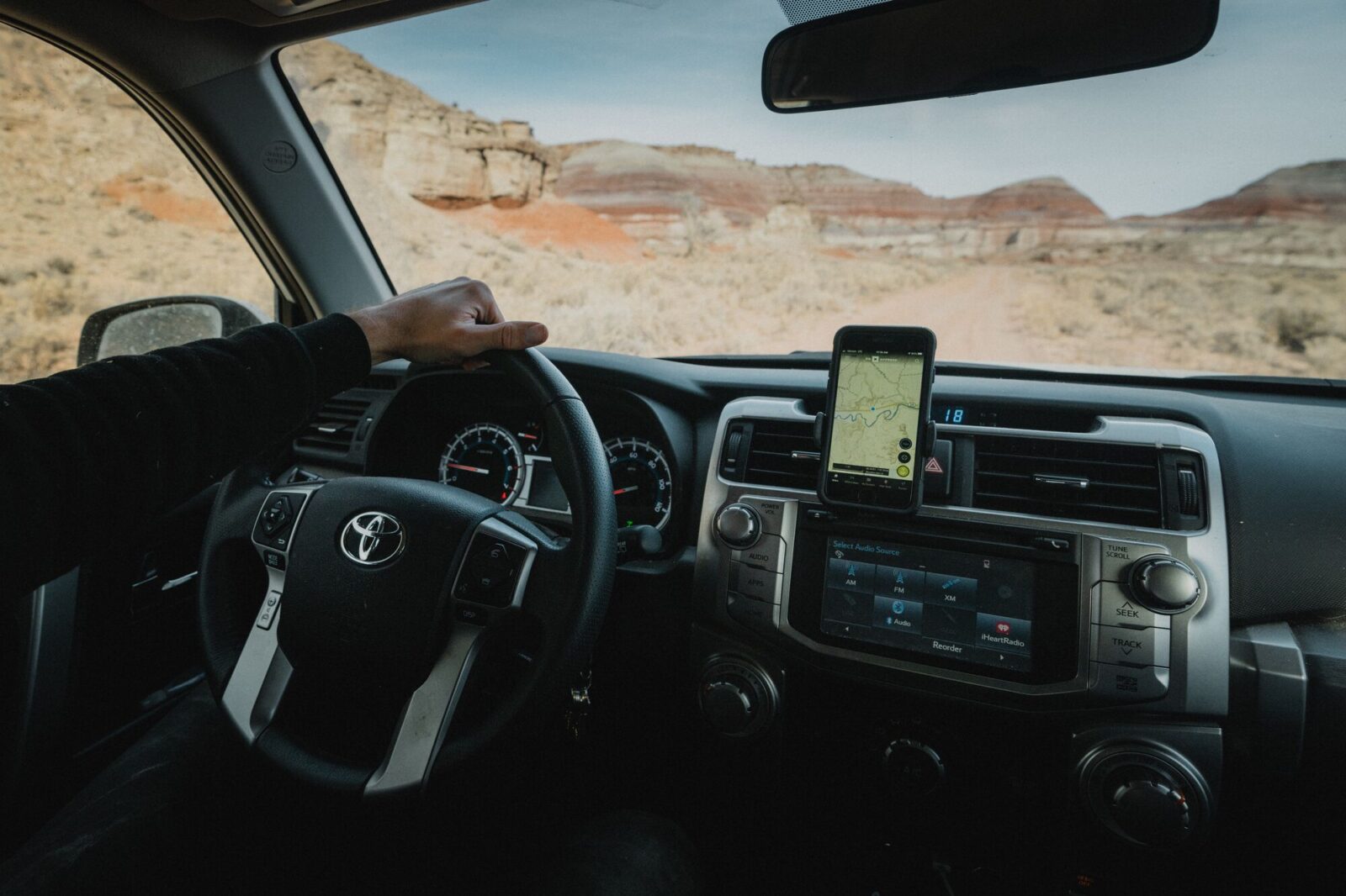 A toyota being driven in a deserted area with an onX app being shown on a phone in the dash.
